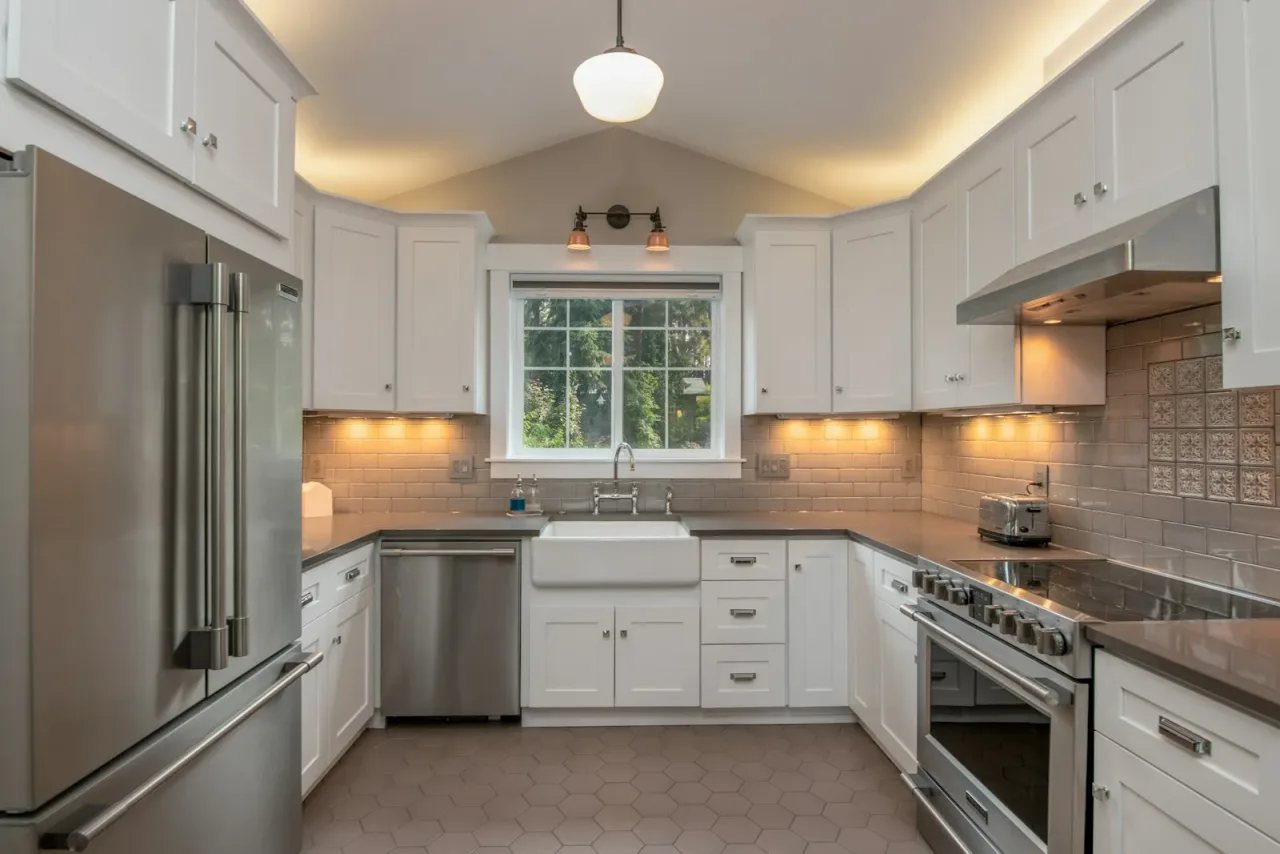 Kitchen after remodel — white shaker cabinets, stainless appliances, farmhouse sink