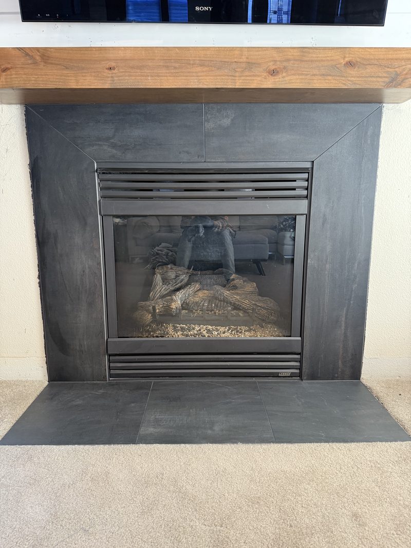 Living-room fireplace with dark slate tile surround and wood mantel