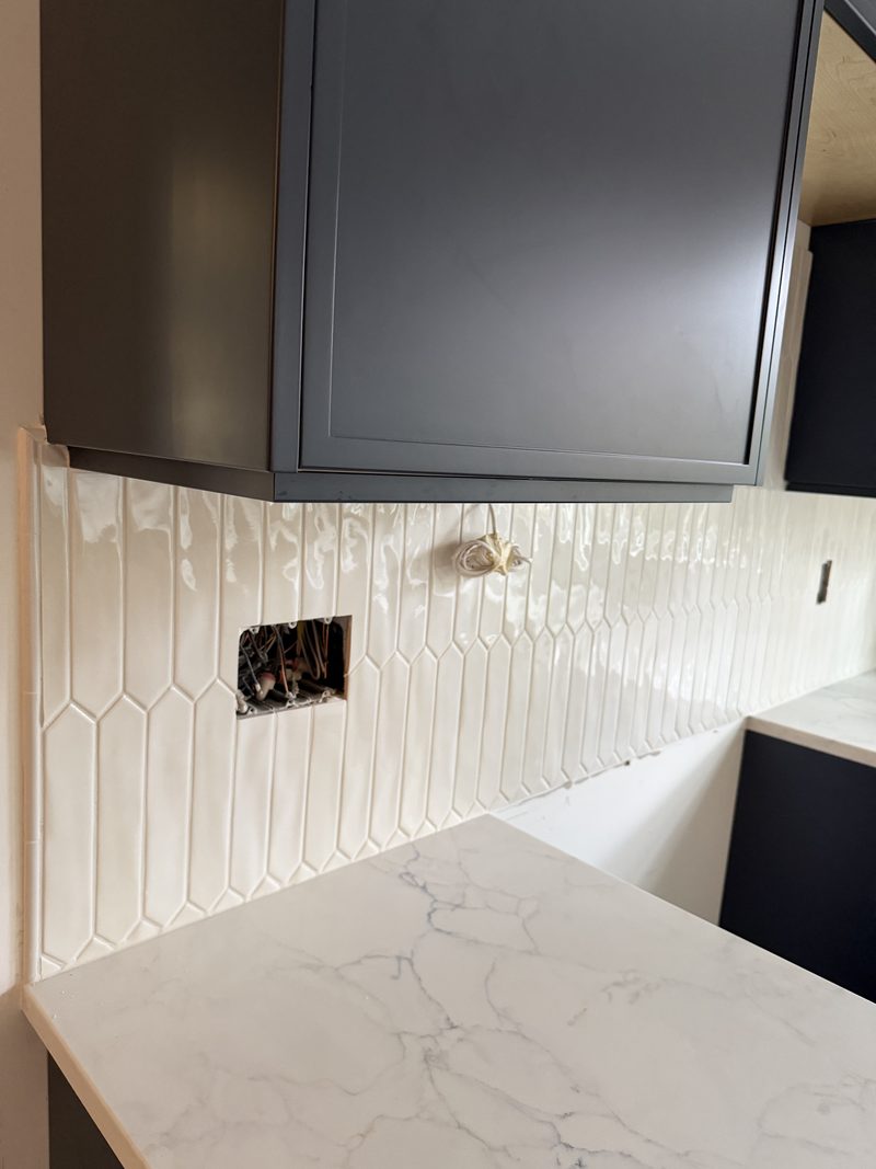 Picket-tile backsplash with quartz counters and matte-black cabinetry