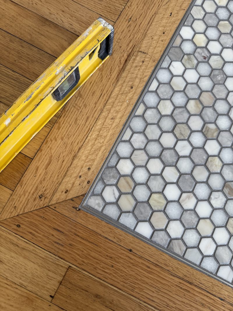 Refinished hardwood meeting hexagon marble tile with a hand-set transition
